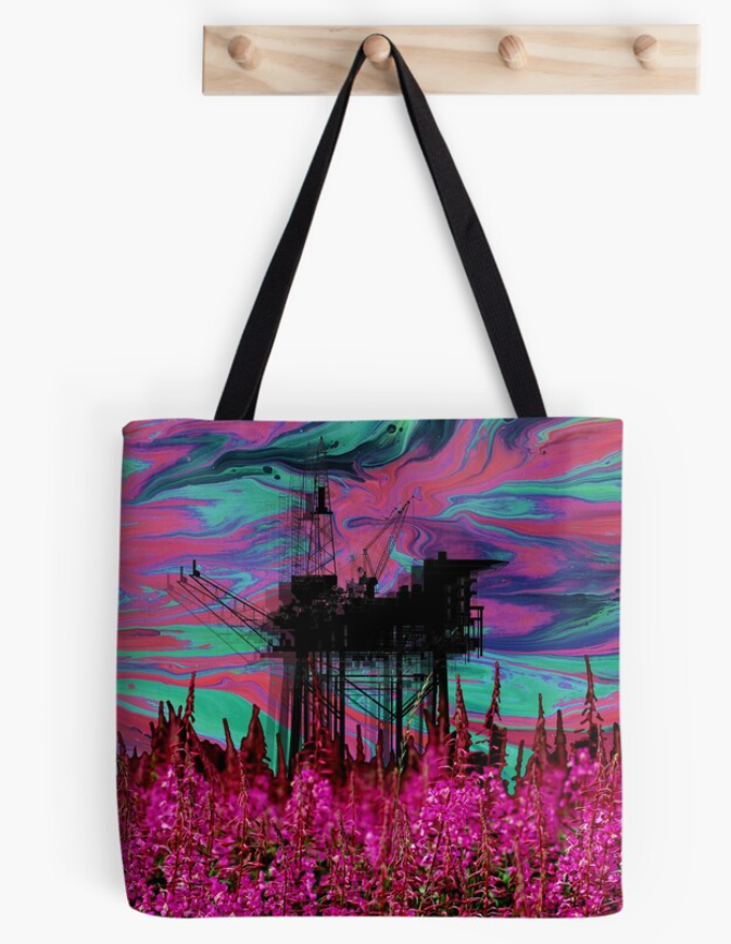 A tote bag with an all over design of a neon cyan and magenta oil spill sky behind a silhouette of an oil rig. The foreground is covered in pink fireweed.